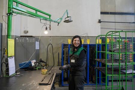 一名在现代金属生产和加工行业工作的妇女正在焊接产品,并为数控机床